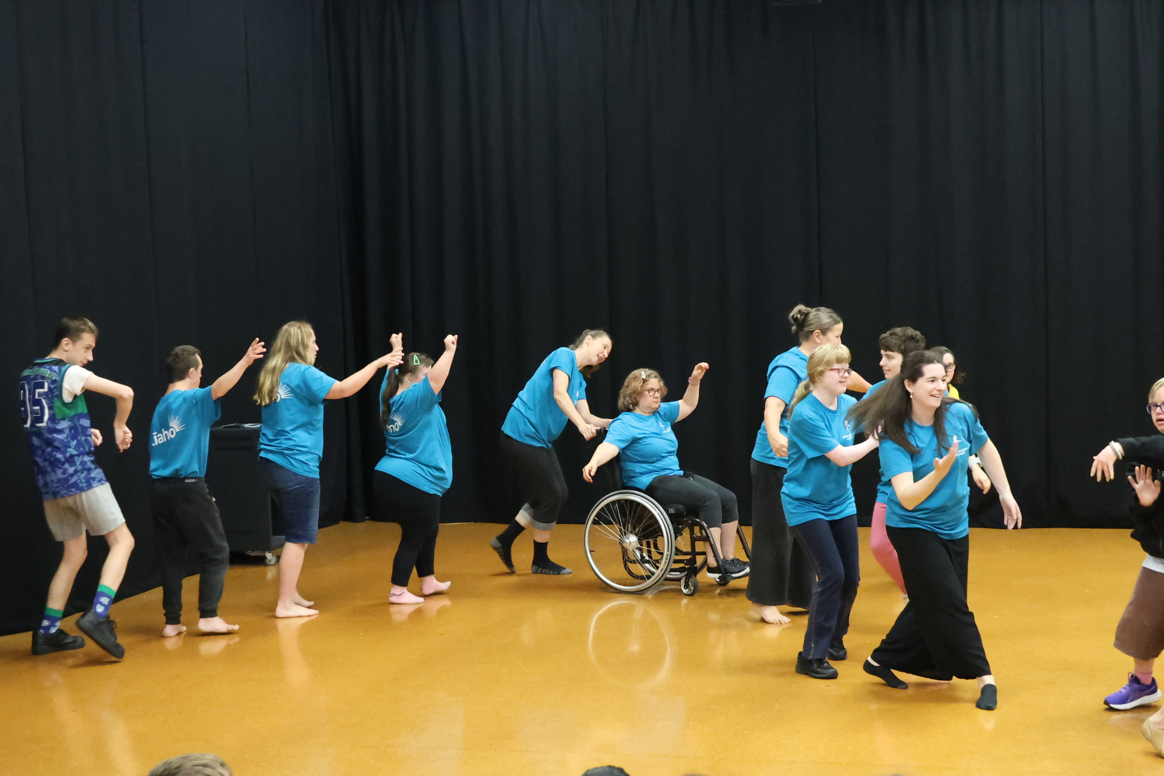 People standing in a curved line to dance, with a person in a wheelchair in the center