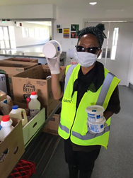 Picture of a volunteer in a mask preparing kai packages